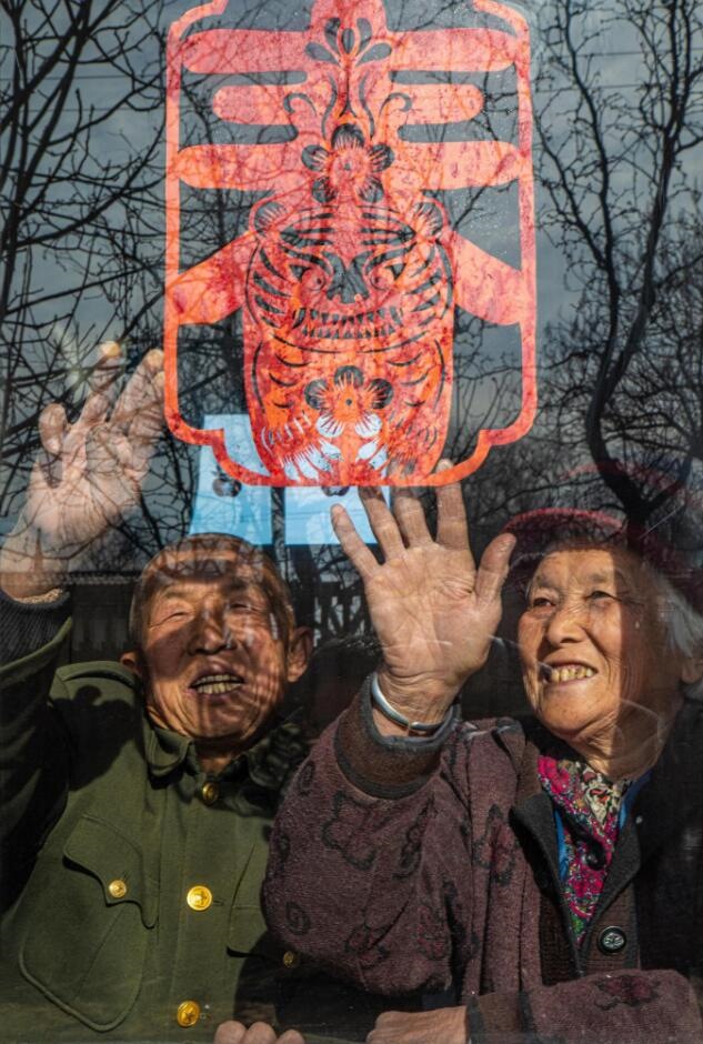 臘月里，霍州市師莊鄉(xiāng)馮南垣村村民師榮光(左)在災(zāi)后重建的新家里貼窗花。(霍州市委宣傳部供圖)
