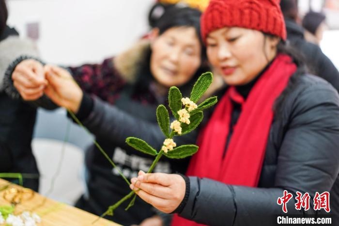 馮燕霞指導(dǎo)姐妹們鉤織月桂葉片。　古良駒 攝