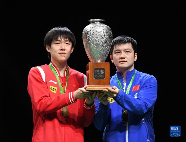 5月27日，樊振東（右）/王楚欽在頒獎儀式上高舉獎杯慶祝。當日，在南非德班進行的2023年世界乒乓球錦標賽男雙決賽中，中國組合樊振東/王楚欽以3比0戰(zhàn)勝韓國組合張禹珍/林鐘勛，奪得冠軍。新華社記者 李亞輝攝