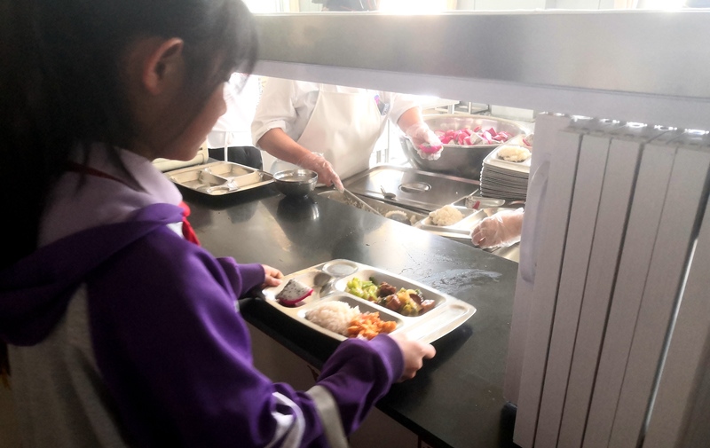 伊金霍洛旗第一小學(xué)學(xué)生正在打飯，今天的飯菜是三菜一湯外加水果，學(xué)生可以多次盛取，吃飽為止。人民網(wǎng)記者 孫博洋攝