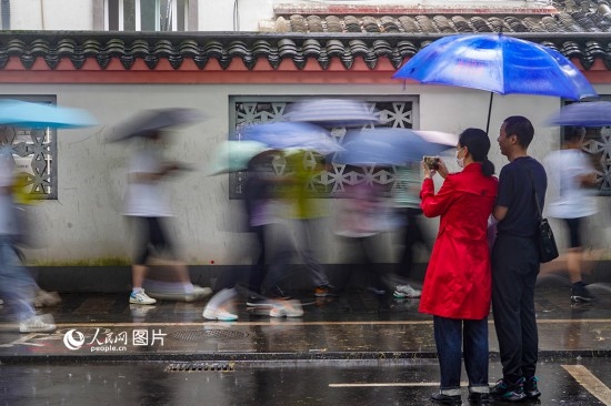 6月7日，在浙江省2023年普通高校招生考試鎮(zhèn)海中學(xué)考點(diǎn)，家長冒雨目送子女進(jìn)入考場。人民網(wǎng) 章勇濤攝