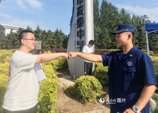 6月7日，遼寧營口老邊區(qū)消防救援大隊(duì)的消防員為高考學(xué)子加油助威。人民網(wǎng)記者 尹柏寒?dāng)z