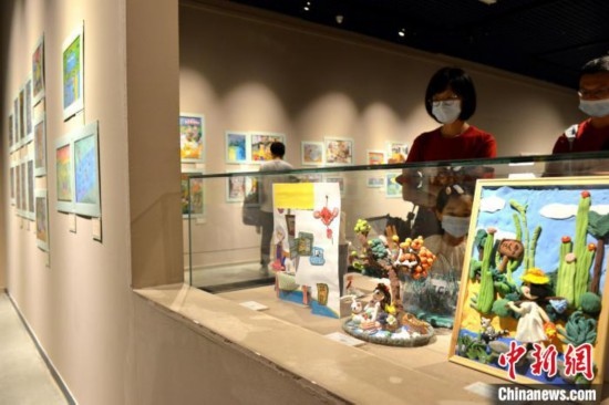 圖為家長(zhǎng)帶著孩子參觀展覽。呂明 攝