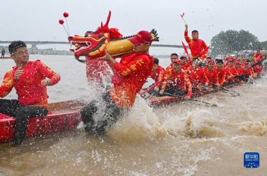 6月22日，在湖南省岳陽市湘陰縣湘江臨資口水域，參加龍舟賽的隊員接“龍頭”下水。