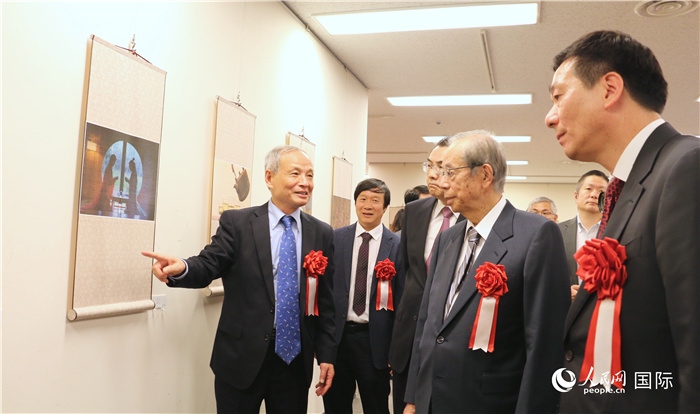 “湖州印象”攝影展主創(chuàng)、世界華人攝影協(xié)會(huì)副會(huì)長(zhǎng)馮學(xué)敏向吳江浩大使、福田康夫前首相等嘉賓介紹展出作品。（人民網(wǎng) 許可攝）