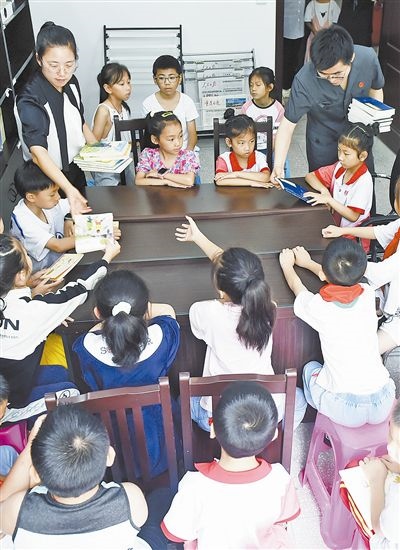  圖④：法院干警為留守兒童發(fā)放暑假讀物。