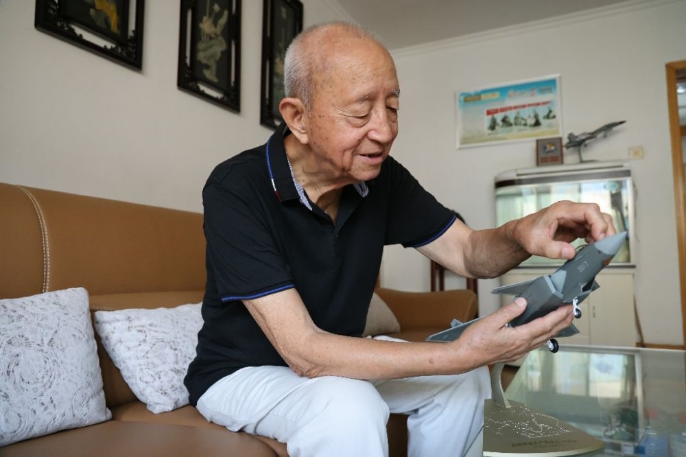 ↑2023年7月24日，新中國(guó)第一代飛行員陶偉在家中擦拭殲-20飛機(jī)模型。新華社發(fā)（張瑞 攝）
