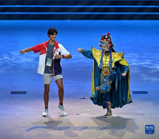7月29日，美國運(yùn)動員杜恩（左）在聯(lián)歡會現(xiàn)場與川劇演員互動。新華社記者 蔡湘鑫 攝