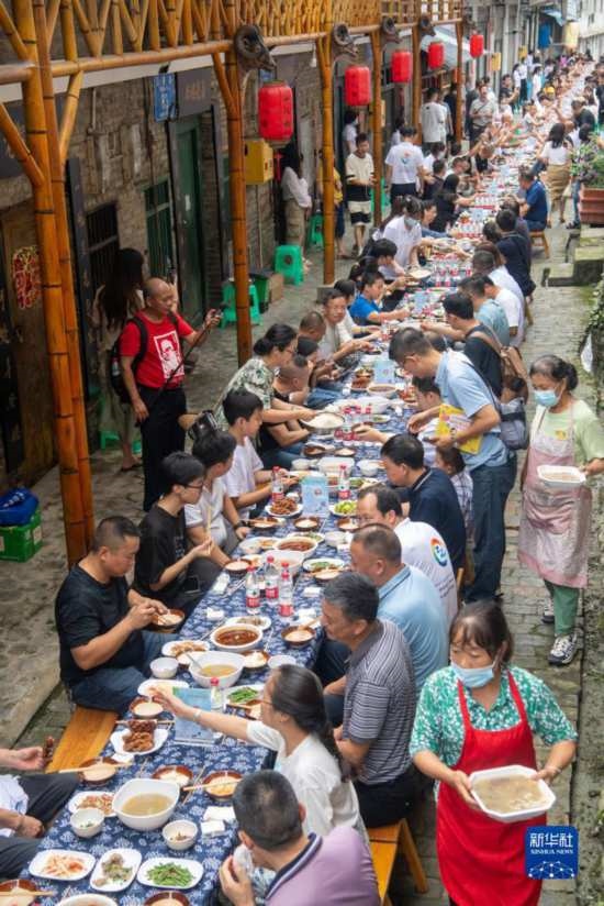 7月29日，在重慶市綦江區(qū)安穩(wěn)鎮(zhèn)，人們?cè)凇懊缂曳蚬?jié)”上吃長(zhǎng)桌宴。新華社記者 唐奕 攝