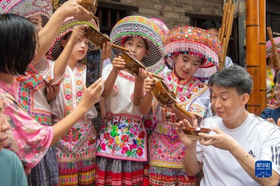 7月29日，在重慶市綦江區(qū)安穩(wěn)鎮(zhèn)，當(dāng)?shù)鼐用裨凇懊缂曳蚬?jié)”上用傳統(tǒng)習(xí)俗向游客表達(dá)祝福。新華社記者 唐奕 攝