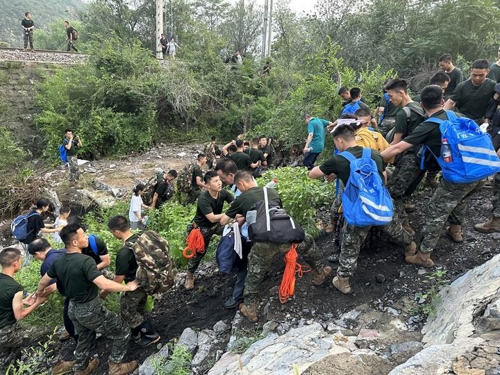 8月2日，Z180次受困列車的旅客在武警北京總隊(duì)機(jī)動第三支隊(duì)官兵的幫助下徒步前往轉(zhuǎn)運(yùn)客車（手機(jī)照片）。新華社記者 王艷剛 攝
