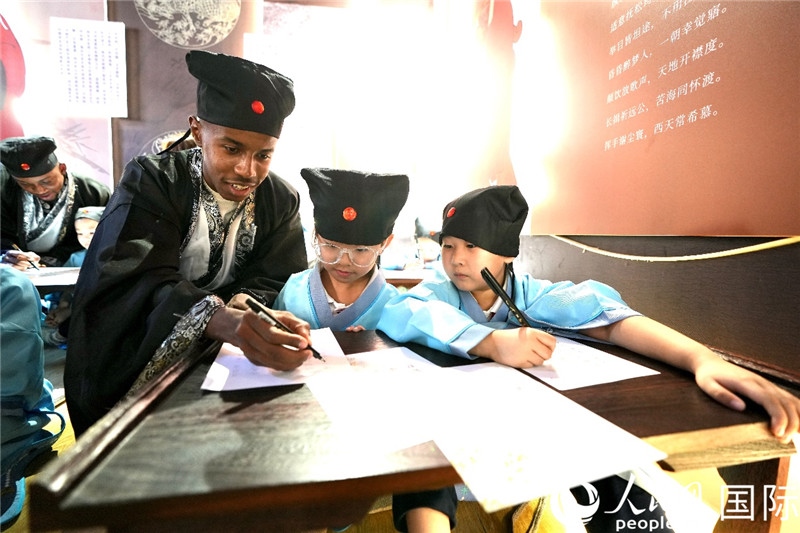 圖為選手與同學(xué)們一起寫書法。人民網(wǎng) 盧鵬宇攝