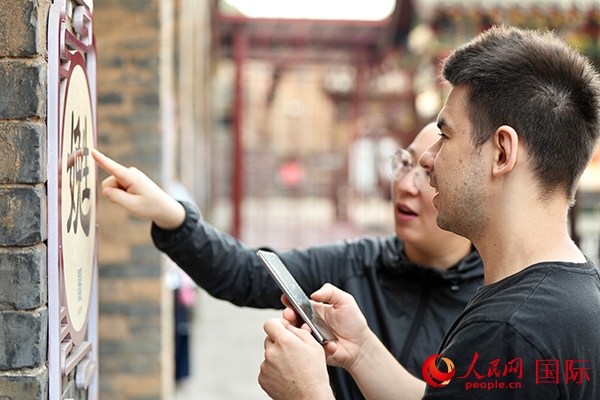 選手安德烈（俄羅斯）在老師指導(dǎo)下學(xué)習(xí)墻壁上張貼的生僻字。人民網(wǎng) 盧鵬宇攝