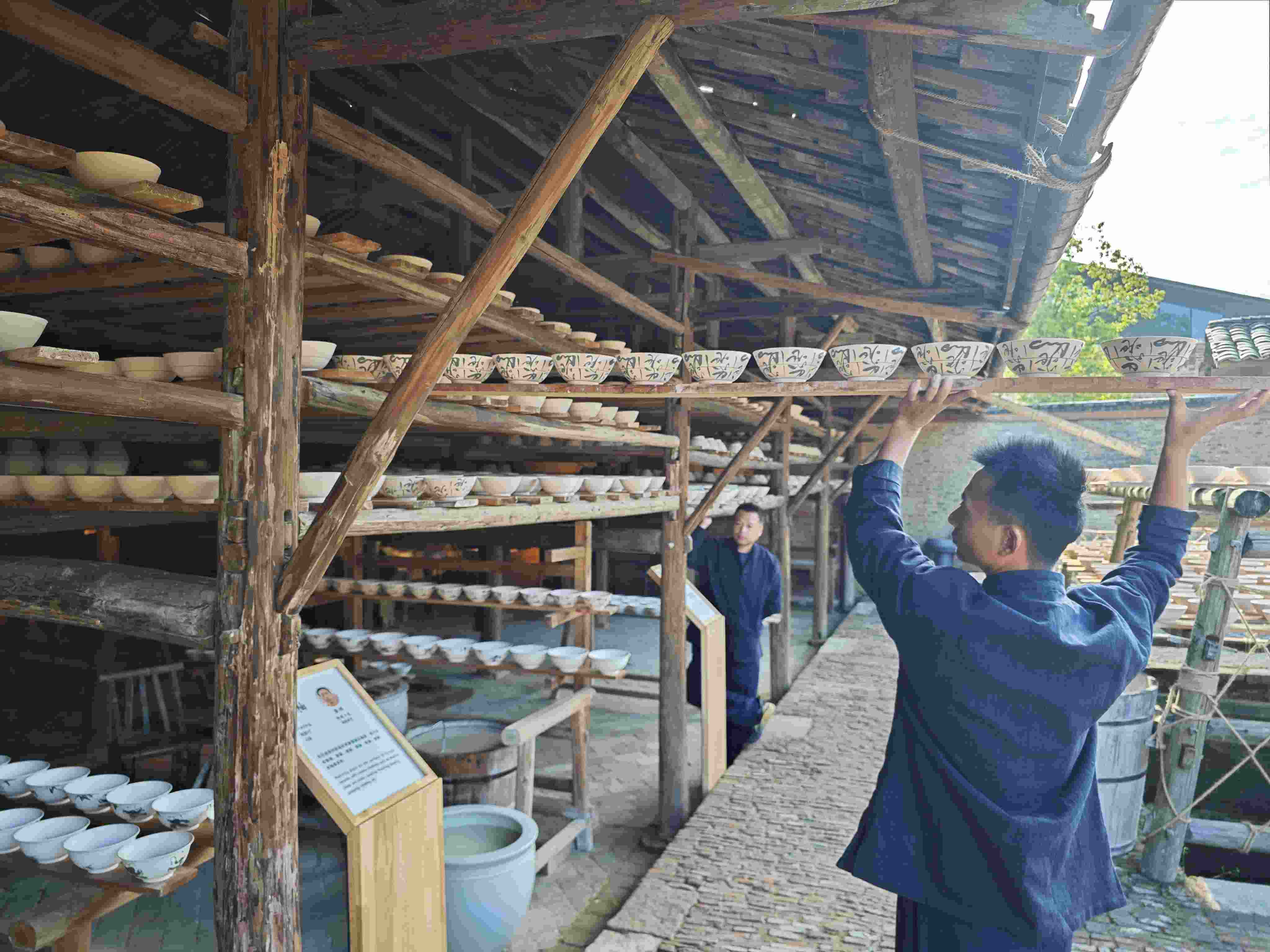 △陶陽里歷史文化街區(qū)里，工匠將陶瓷工藝品放到架上晾干。（總臺央視記者彭漢明拍攝）