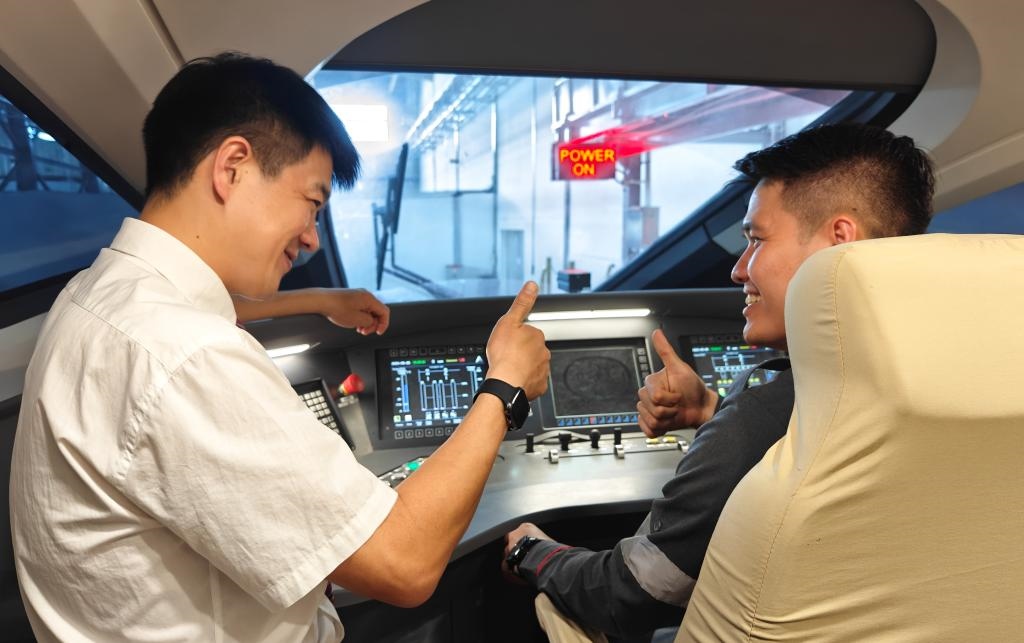 8月25日，在印度尼西亞萬隆的雅萬高鐵德卡魯爾動車所內(nèi)，中國師傅穆振（左）在向印尼火車司機(jī)塞蒂亞萬講解動車組出庫前的上電作業(yè)。