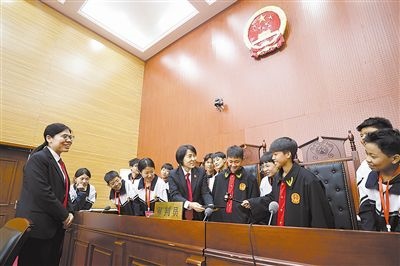 圖③：同學們穿法袍、敲法槌，爭做“小法官”。
