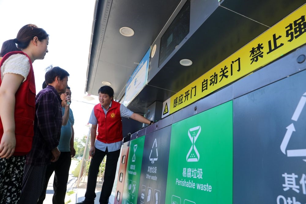 在安徽省合肥市長豐縣莊墓鎮(zhèn)棗林社區(qū)，志愿者指導(dǎo)居民使用智能垃圾分類回收設(shè)備（2023年9月1日攝）。新華社記者 曹力 攝