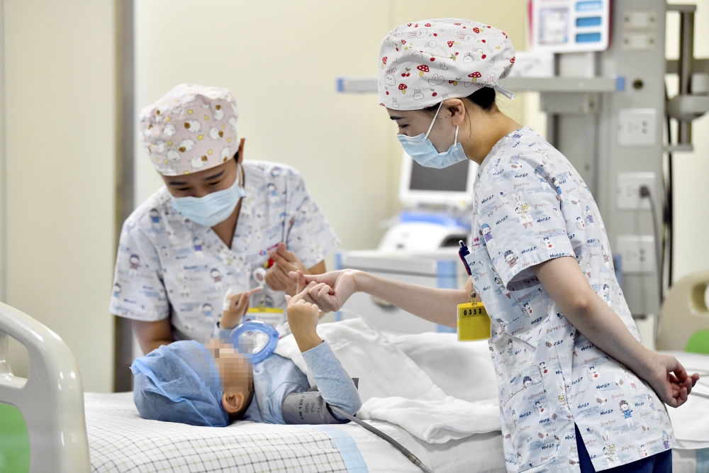 在山東省棗莊市婦幼保健院兒童ICU病房，醫(yī)護人員為完成靶向治療藥物諾西那生鈉的4歲脊髓性肌萎縮癥患兒加油鼓勁（2022年1月1日攝）。諾西那生鈉注射液是我國首個獲批治療脊髓性肌萎縮癥的進口藥物，2019年進入中國市場時，每針價格近70萬元。在2021年國家醫(yī)保目錄藥品談判中，以3.3萬元每針的價格進入新版醫(yī)保藥品目錄。新華社記者 郭緒雷 攝
