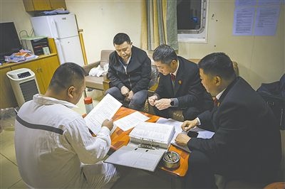 圖②：法官向船長講解相關(guān)法律規(guī)定，查看船舶資料，并與船方辦理扣押船舶的手續(xù)。