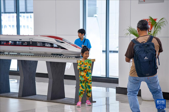 1月24日，在印度尼西亞雅加達(dá)哈利姆站候車大廳，一名小朋友和雅萬高鐵高速動車組模型合影。新華社記者 徐欽 攝