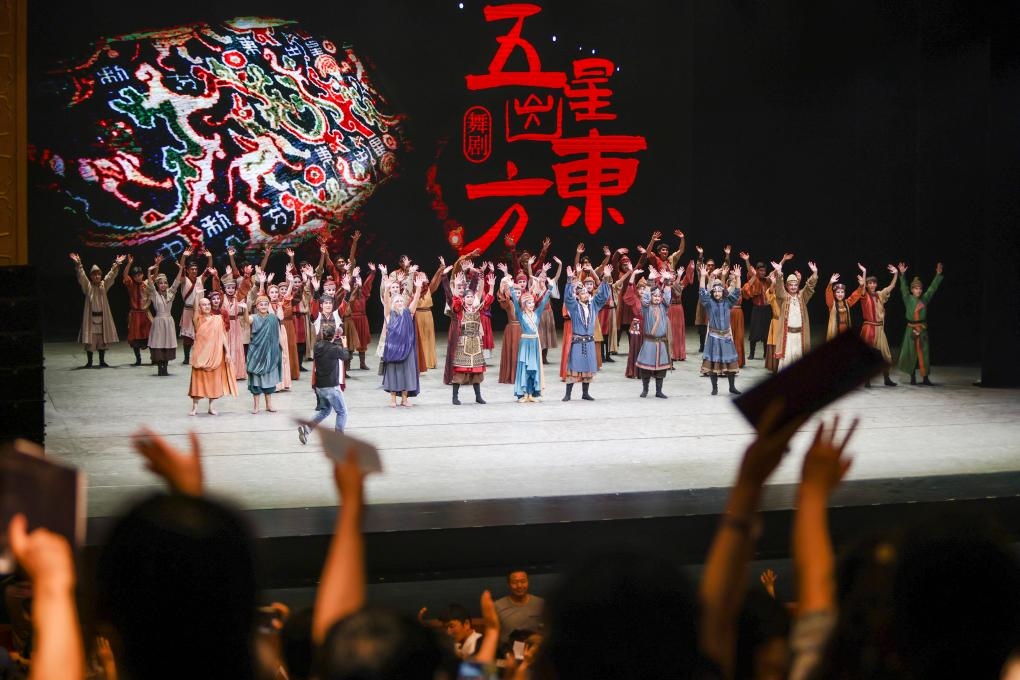 2023年7月31日，新疆和田地區(qū)新玉歌舞團(tuán)在烏魯木齊京劇院演出舞劇《五星出東方》后和觀眾互相揮手致意。這場(chǎng)演出是第六屆中國(guó)新疆國(guó)際民族舞蹈節(jié)的參演劇目之一，曾榮獲國(guó)家“文華獎(jiǎng)”等。新華社記者 郝昭 攝