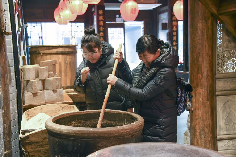 游客在平遙古城東湖老醋坊內(nèi)體驗(yàn)陳醋發(fā)酵打耙（2022年1月28日攝）。新華社發(fā)（梁生仁攝）