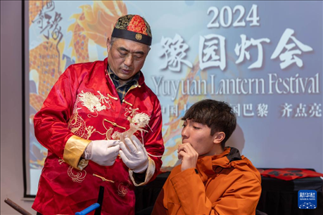 1月28日，在上海豫園舉行的民俗活動上，美國馬斯卡廷中學(xué)學(xué)生在非遺傳承人的指導(dǎo)下吹糖偶。 新華社記者 王翔 攝