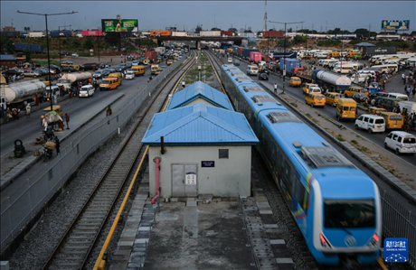 3月4日，在尼日利亞拉各斯，一列輕軌藍線列車行駛至公路交通擁堵路段附近。新華社記者 韓旭 攝