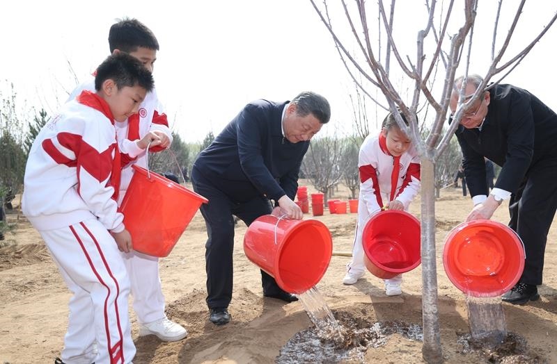 2024年4月3日，習(xí)近平總書記同少先隊(duì)員一起給剛栽下的樹苗澆水。