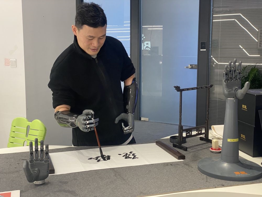 2024年3月29日，在浙江強腦科技有限公司展廳內(nèi)，失去雙手的產(chǎn)品體驗官倪敏成依靠智能仿生手寫毛筆字。新華社記者 魏一駿 攝