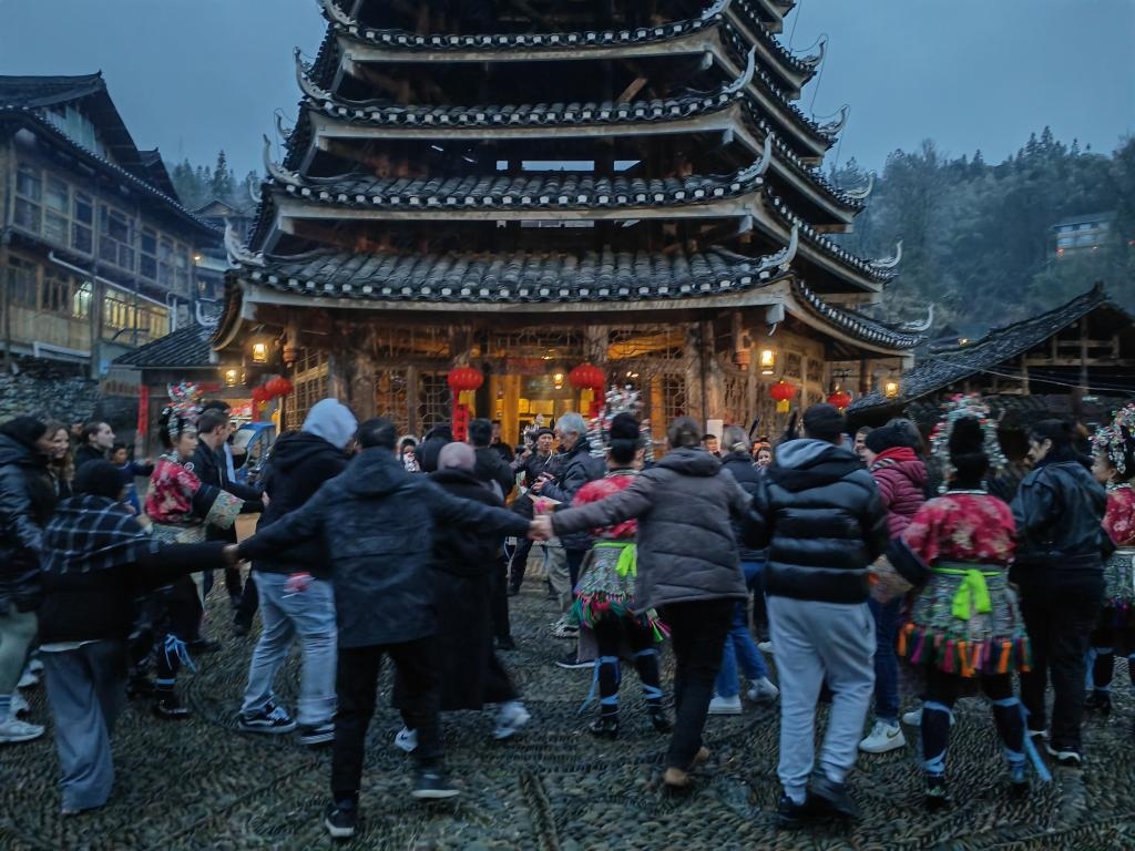 法國(guó)青年與當(dāng)?shù)卮迕駹渴痔?。新華社記者 羅羽 攝
