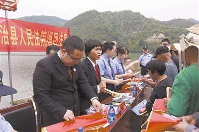 法院干警及相關部門工作人員對群眾進行生態(tài)環(huán)境保護普法教育。
