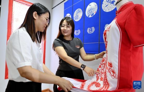 5月31日，在衡水市阜城縣一家剪紙工作室，游客在觀賞帶有剪紙元素的旗袍。