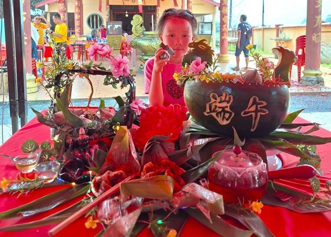 小朋友展示學(xué)裹粽子的成品照。組委會供圖