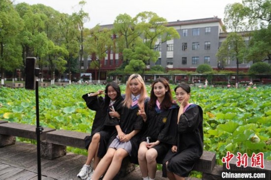 6月19日，時(shí)值一年畢業(yè)季，四川大學(xué)望江校區(qū)荷花池里的荷花盛開(kāi)，成為了畢業(yè)生們的打卡圣地，吸引了眾多畢業(yè)生拍照留念。圖為畢業(yè)生在荷花池邊拍照留念。中新社記者 安源 攝