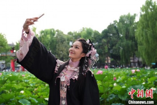 6月19日，時(shí)值一年畢業(yè)季，四川大學(xué)望江校區(qū)荷花池里的荷花盛開(kāi)，成為了畢業(yè)生們的打卡圣地，吸引了眾多畢業(yè)生拍照留念。圖為畢業(yè)生在荷花池邊拍照留念。中新社記者 安源 攝