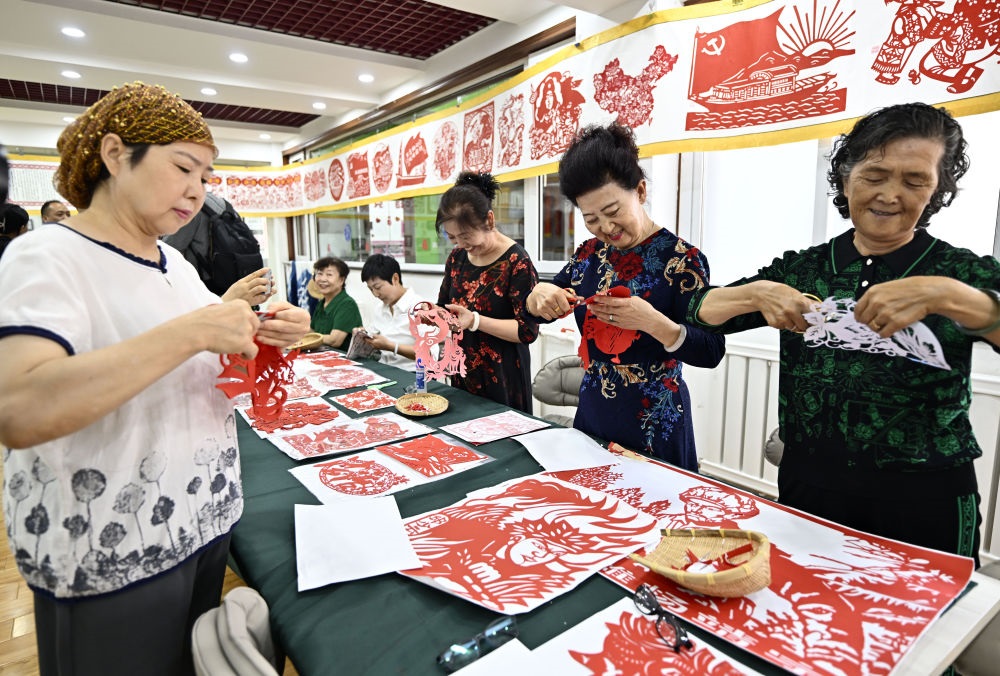 6月19日，長(zhǎng)城花園社區(qū)居民在社區(qū)“才藝堂”制作剪紙。