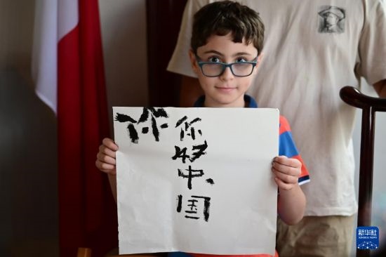 7月4日，在馬耳他桑塔露琪亞市的中國(guó)古典園林“靜園”，一名男孩展示他的書法作品。新華社發(fā)（喬納森·博格 攝）