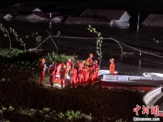  7月6日凌晨3時，在湖南岳陽華容縣團洲垸洞庭湖一線堤防，救援人員剛剛完成一次救援任務(wù)，遠處是被淹的民房。中新社記者 白祖偕 攝
