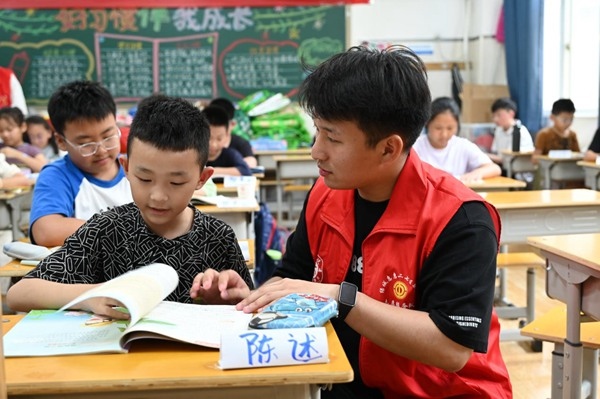 鄭州市二七區(qū)暑托班的志愿者輔導(dǎo)孩子寫作業(yè)。人民網(wǎng)記者王玉興攝