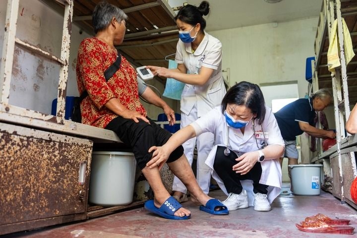 2024年7月30日，在湖南省湘潭縣河口中學(xué)安置點，醫(yī)務(wù)人員為受洪水影響而轉(zhuǎn)移安置的群眾檢查身體。 新華社記者 陳思汗 攝