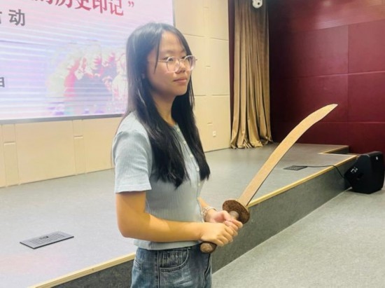 圖為南開大學(xué)社會實(shí)踐隊(duì)學(xué)生代表呼月紅在學(xué)術(shù)交流活動現(xiàn)場，展示河間調(diào)研行中獲贈的一戰(zhàn)華工蔡世春曾使用過的一把大刀。林卓瑋 攝