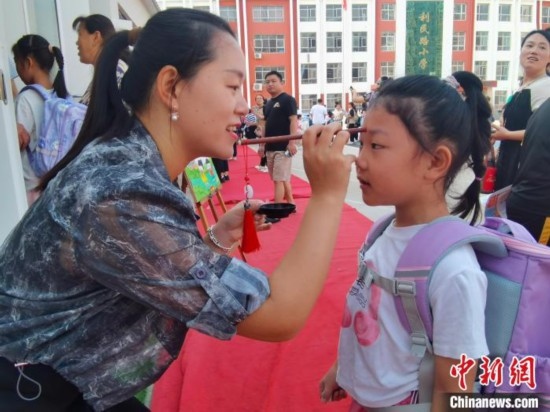 圖為衡水市利民路小學，老師為學生點朱砂痣，寓意開啟智慧。張松 攝