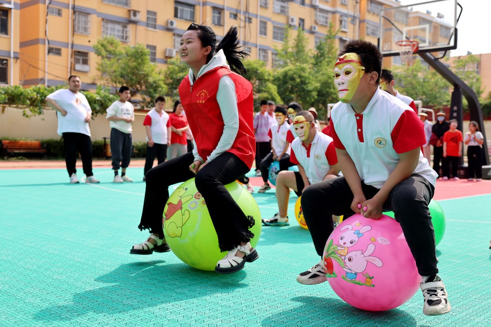 2024年5月17日，在山東省棗莊市市中區(qū)特殊教育中心，青年志愿者與智力障礙學(xué)生一起做游戲。新華社發(fā)（孫中喆攝）