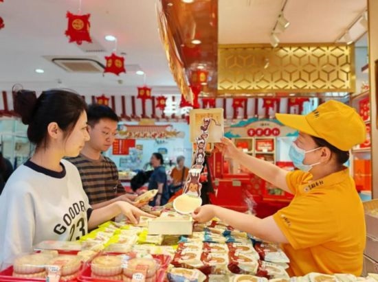 北京稻香村一家門店內(nèi)，售貨員向顧客展示新上市的月餅禮盒。（受訪者供圖）