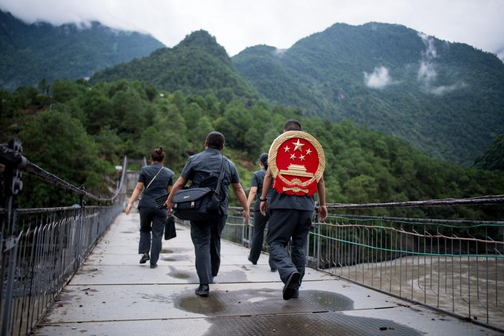 云南省怒江傈僳族自治州貢山縣人民法院法官鄧興背著國徽與同事們跨過怒江（2019年8月30日攝）。怒江高山峽谷眾多，交通不便，為方便群眾、更好地開展法律服務(wù)，背著國徽攀高山、過索橋、躲落石、鉆老林……成為鄧興法官的工作常態(tài)。新華社記者 江文耀 攝