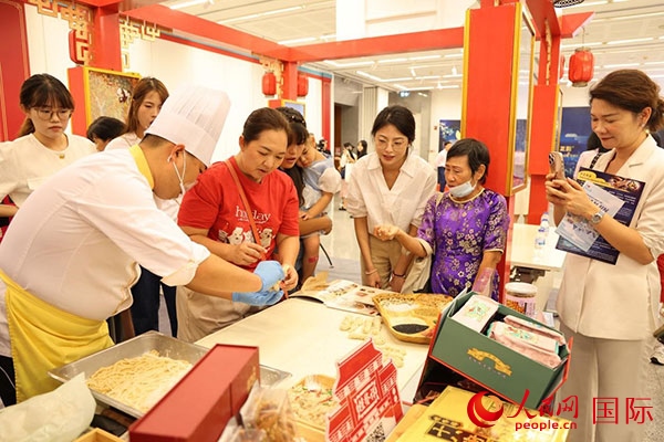 演出前，在天津桂發(fā)祥十八街麻花制作技藝非遺體驗展臺前，泰國民眾體驗天津麻花制作。人民網(wǎng)記者 楊一攝