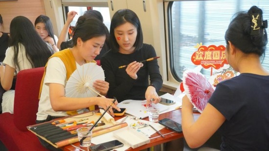 10月1日，旅客們?cè)贕1634次列車(chē)上給油紙傘作畫(huà)。新華社記者周義 攝