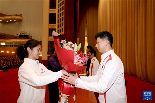 11月15日，一名學(xué)生代表在報(bào)告會(huì)上向乒乓球運(yùn)動(dòng)員馬龍（右）獻(xiàn)花。新華社記者 李明 攝