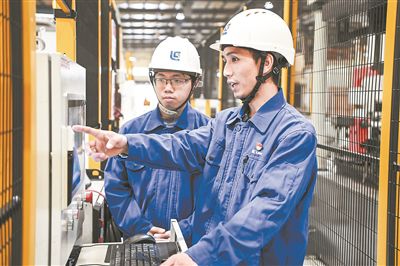 在廣西柳工機械股份有限公司生產(chǎn)車間內，一名高級技師（右）給徒弟講解數(shù)控設備操作細節(jié)。新華社記者 曹祎銘攝